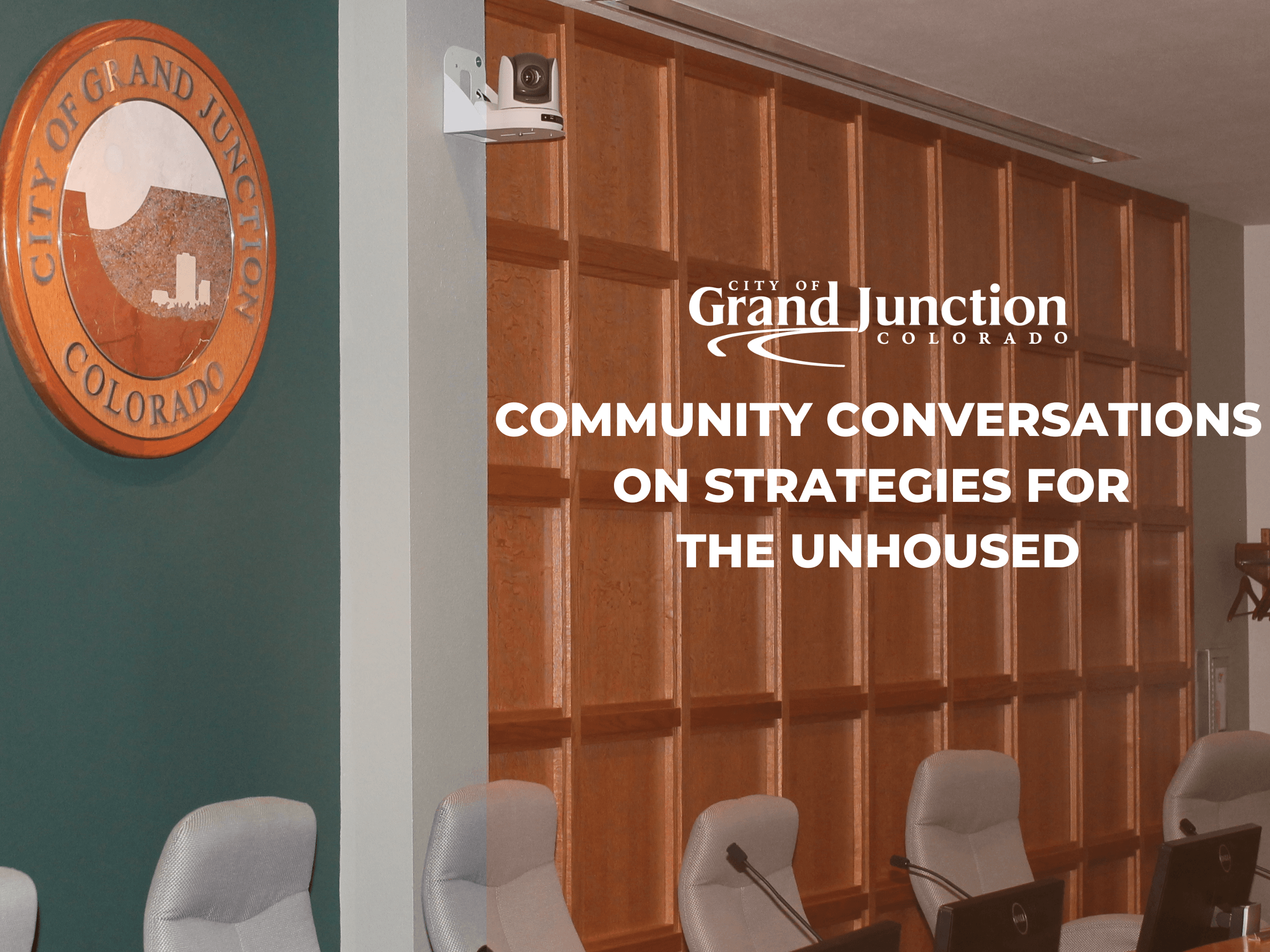 Inside an auditorium with a seal on the back wall. Text on graphic. 