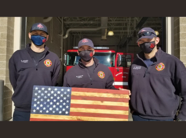three firefighters holding wooden flag