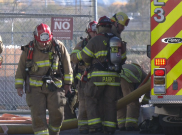 Firemen next to truck with hose deployed