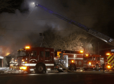 Fire Truck with ladder extended, smoke and flames in the distance