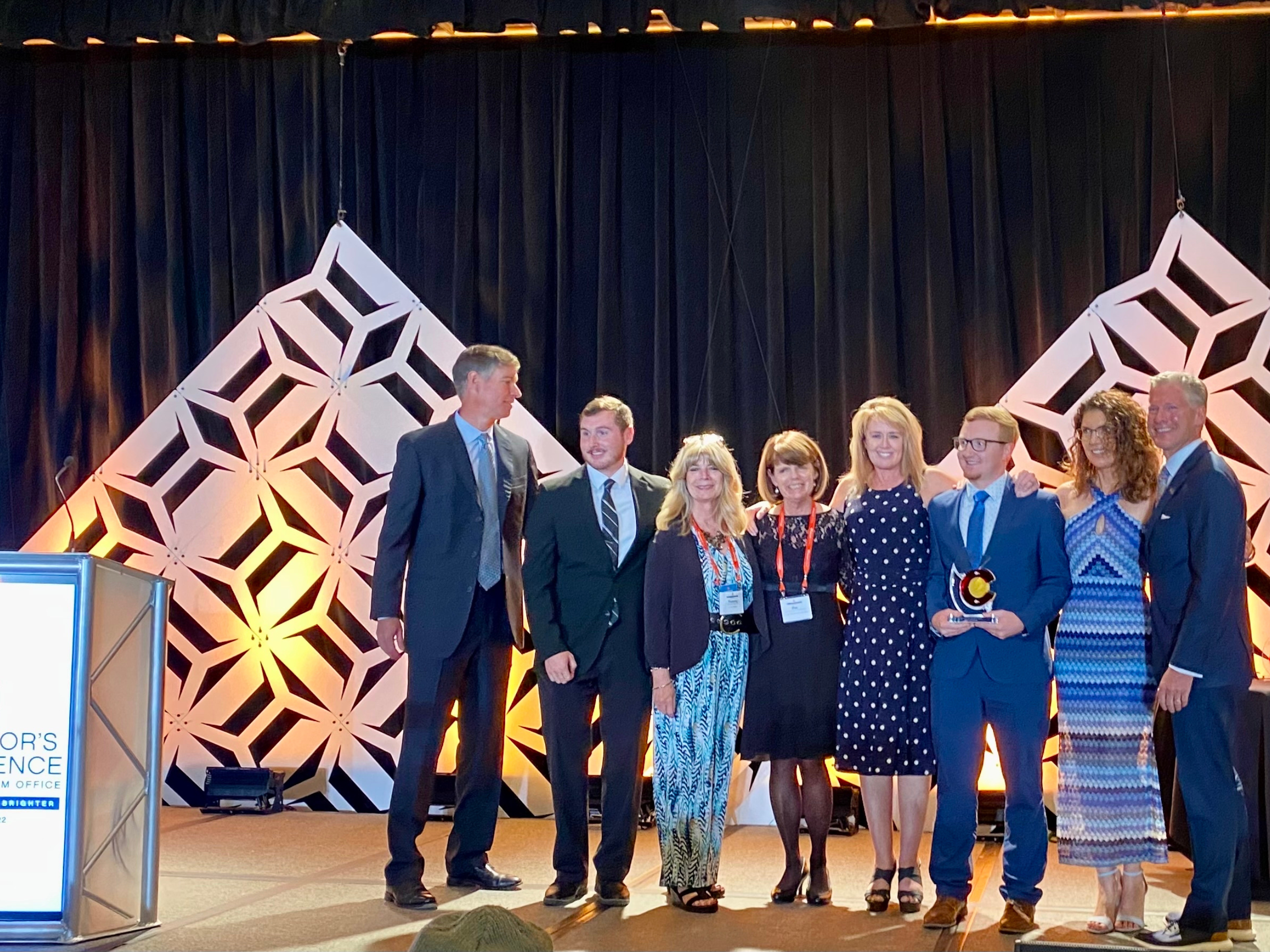 group of people standing on stage accepting award