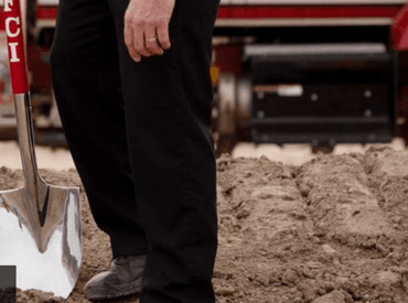 Picture of someone holding a shovel during a ground breaking of a new construction