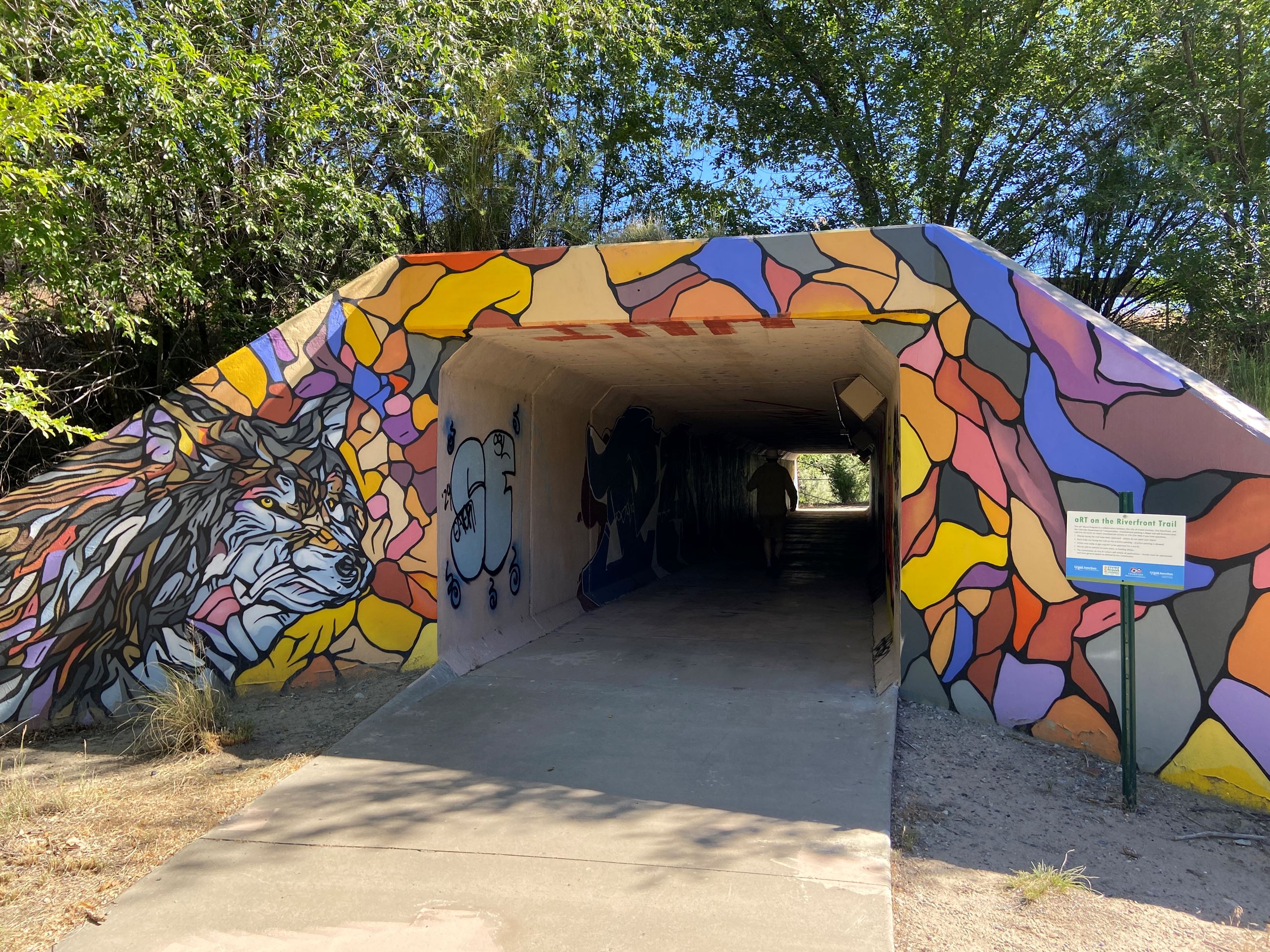 Mural over entrance of bridge in mosaic style with a wolf to the left