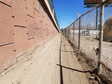 Clean sidewalk between wall and fence.